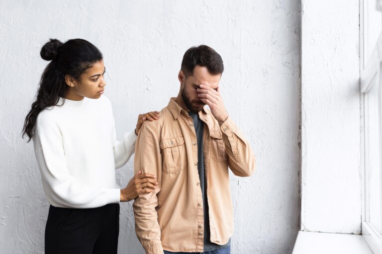 hombre triste siendo consolado por mujer en una sesion de terapia de grupo